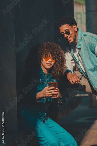 young latin couple with mobile phone on the street
