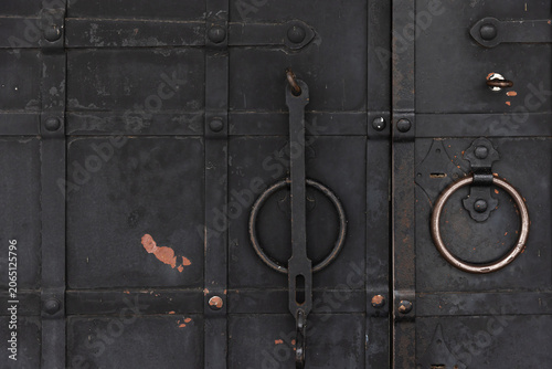 Obraz na plátně Close-up of a rustic iron door showing circular metal ring handles, a weathered
