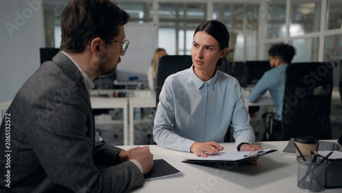 Two Caucasian business office workers discuss papers stats businesswoman talking with businessman consulting intern corporate education trainee mentor woman with man talk showing documents mentoring