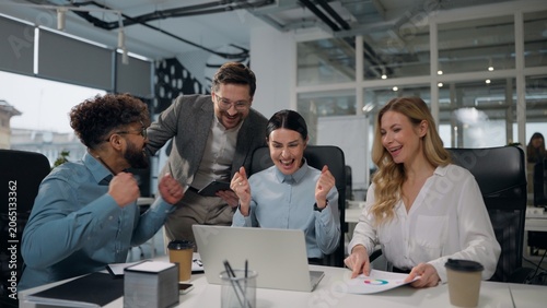 Four multiethnic business people working together with laptop talking winning job success giving high five celebrating multiracial businessmen and businesswomen colleagues win achieve team in office