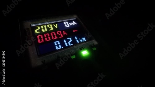 Electrical measuring device with colorful display showing voltage and power in the dark