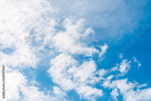 Natural blue sky background with soft scattered clouds. Light wispy clouds against a vibrant blue sky.