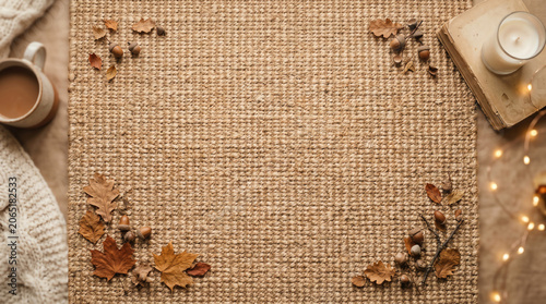 cozy autumn flat lay with hot coffee cup burning candle and dry leaves framing empty woven mat