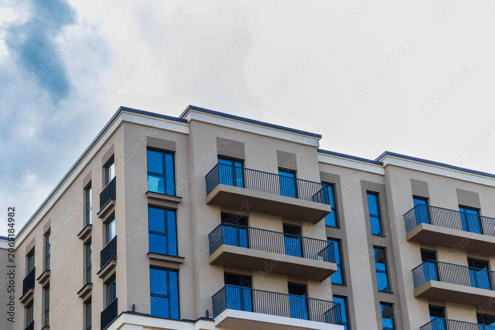 Fototapeta premium Modern apartment building facade with balconies against a blue sky. Urban