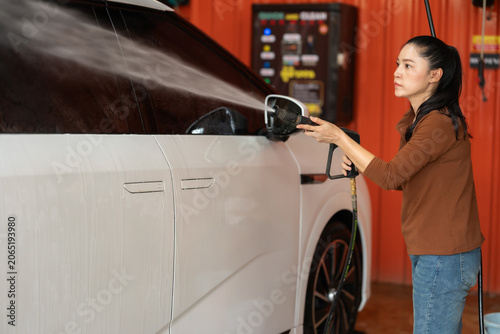 Fotografie woman washing car with water hose in a self-service car wash station