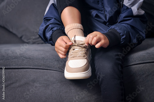 Fotografia Close up of a boy's hands tying the laces of his new beige sneakers, getting ready for the first day of back to school