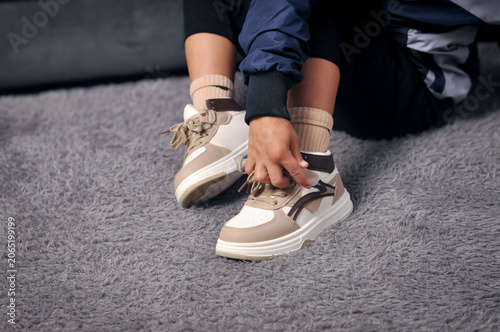 Tableau sur toile Close up of a boy's hands tying the laces of his new beige sneakers, getting ready for the first day of back to school
