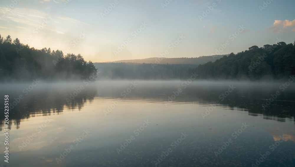 Fototapeta premium Soft morning glow illuminating a peaceful lake with still water and quiet surroundings
