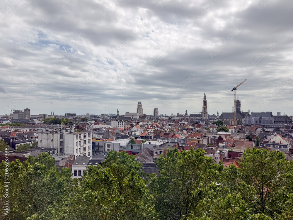 Fototapeta premium Antwerpen, België – Panoramic City Skyline with Cathedral Tower and Rooftops Under Cloudy Sky