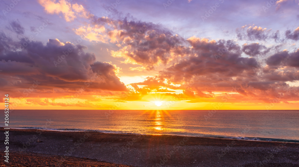 Obraz premium Dramatic seascape of sunset or sunrise sky with clouds during morning or evening. Dramatic sunset over the sea with orange clouds and sun above ocean water