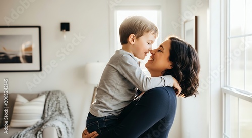 Mother holding son in sunlit room with framed art
