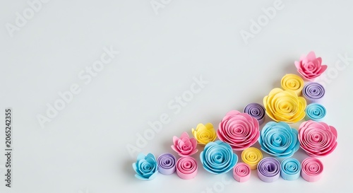 Pastel paper flowers arranged diagonally on a white background