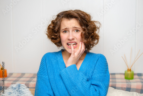 young woman with dental braces showing discomfort and anxiety, biting her finger with a worried expression, highlighting orthodontic pain or oral health issues