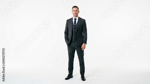 A man in a suit standing against a white background, with a confident smile.