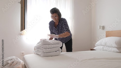 Elderly woman stripping bed 
