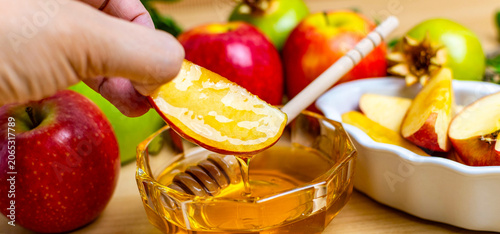 Hand dipping apple slice in honey for rosh hashanah
