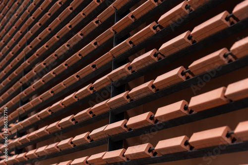 Close-up of contemporary architectural details featuring repeating rows of orange clay bricks installed on a metal frame.