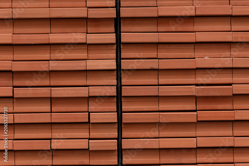 Close-up of contemporary architectural details featuring repeating rows of orange clay bricks installed on a metal frame.