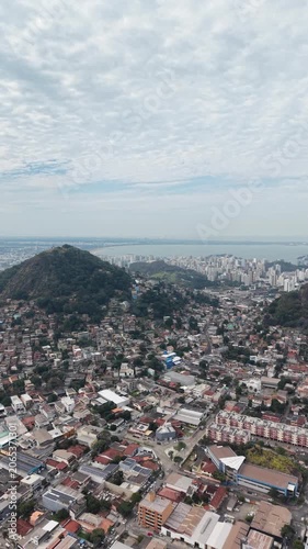 Panoramic aerial view of Vitória, Espírito Santo, Brazil, showcasing the urban skyline, bays, islands, hills, and coastal landscape beneath a dramatic cloudy sky.