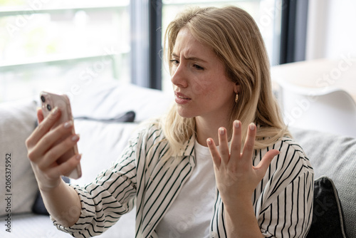 Valokuva Frustrated young adult woman reacting to confusing bad news on her mobile phone,