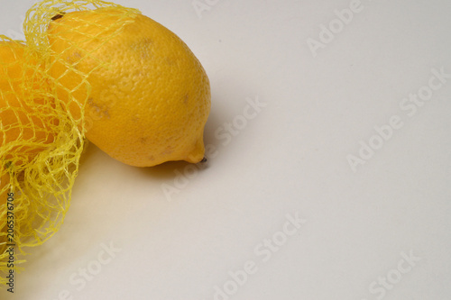 yellow lemon in a yellow mesh  on a white background corner composition horizontal layout, lemons close up with generous copy space,