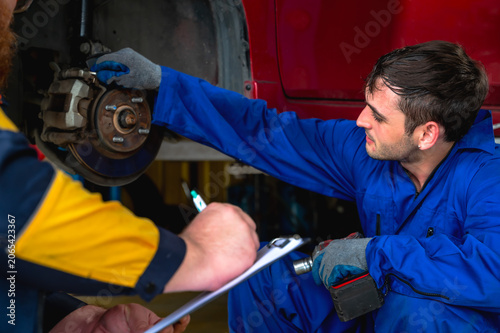 Quadro su tela Handsome  male auto mechanic in uniform focusing on repairing and maintaining ca