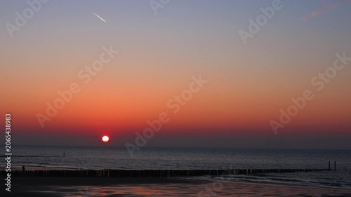 Cinematic Sunset Over the North Sea Beach in Cadzand Netherlands with Calm Waves and Glowing Orange Sky