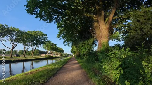 Scenic Canal Towpath Walk in Summer — POV Nature Trail Footage with Tree Shadows and Calm Water