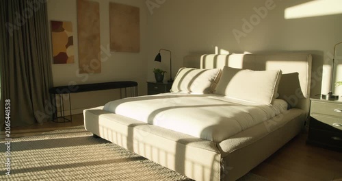Sunlight is streaming bands across bed through window while camera is moving to highlight pillows