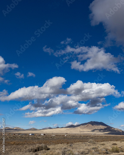 White puffy clouds above Interstate 80 crossing barren landscape