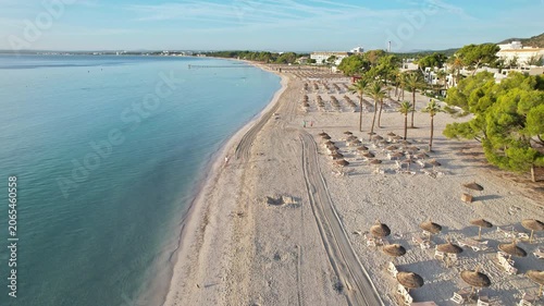 Coastal tourism destination presents expansive beach, crystal water, leisure seating beneath in Mallorca