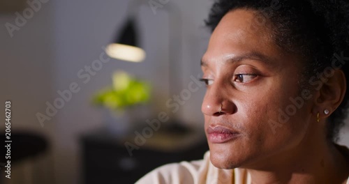 Adult African American woman sitting home thinking, nose ring or hoop tracking gaze down up under la