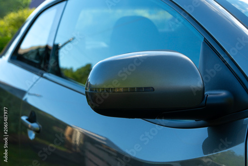 Side mirror, door and fragment of a car in the evening light on the street in summer