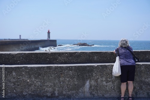 Woman looking at a lighthouse on the coast porto