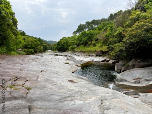 The suspension bridge and unique granite riverbed with potholes at Ayumodoshi Natural Park on Tsushima Island, Nagasaki Prefecture, Japan.
