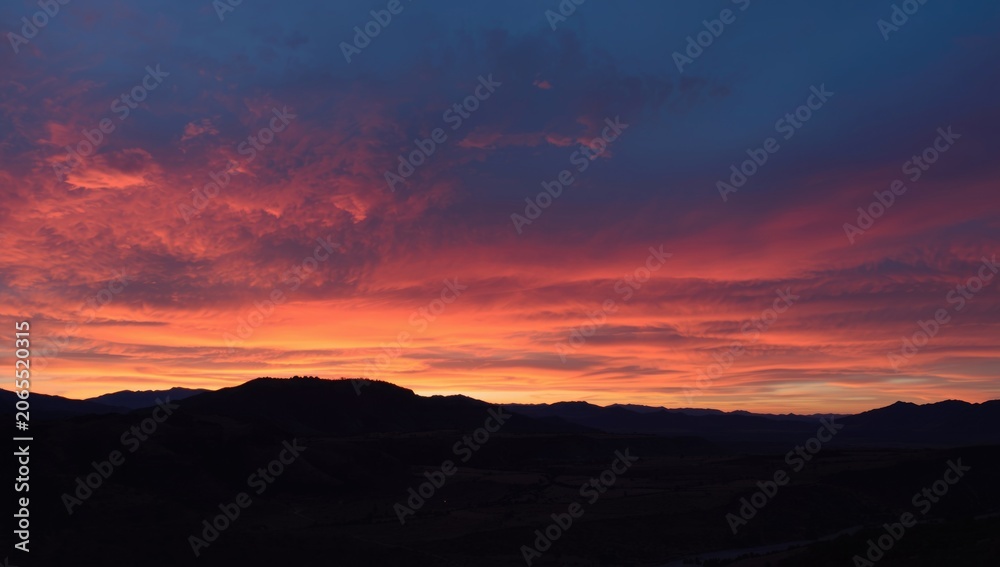Obraz premium Vibrant sunset over mountain silhouette and valley