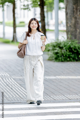 コーヒーを片手にオフィス街を歩く日本人女性
