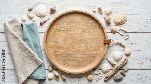 Wooden round tray with seashells and linen napkins on white rustic table