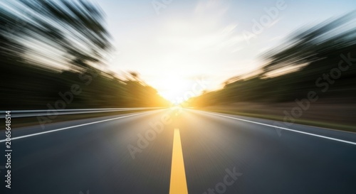 Driving down a highway at sunset with motion blur and the sun shining in the distance