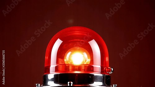 Red emergency siren light flashing against a dark background