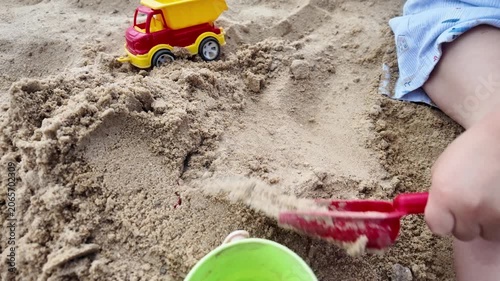 Toddler digging sand with toy shovel close up child playing in sandbox summer outdoor activity and development