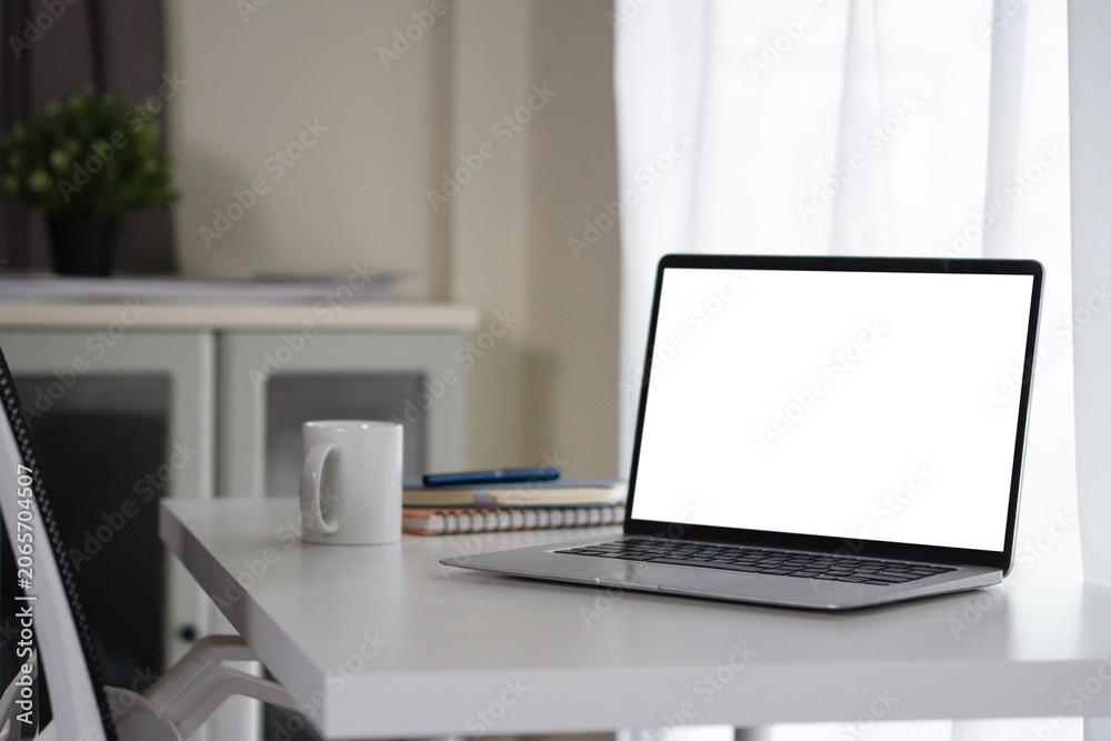 Fototapeta premium Laptop with Blank White Screen on Clean White Desk in Modern Home Office Workspace with Coffee Mug and Notebook