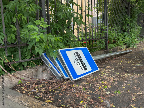 Photography Roadwork signs lean against fence beside overgrown sidewalk in Moscow, temporary traffic management equipment, construction area