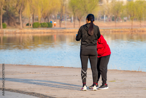 People walking and taking photos on riverside boardwalk in vibrant spring park