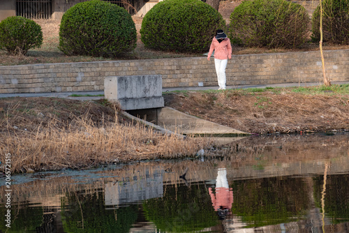 People walking and taking photos on riverside boardwalk in vibrant spring park