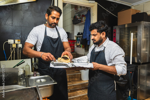 Indian restaurant staff wrapping takeaway food