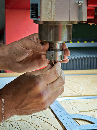 Close up of CNC router operator hands changing drill bit on spindle