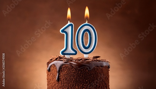 birthday chocolate cake with burning candle as a number ten on brown background