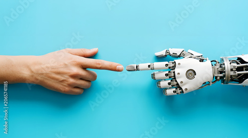 Human finger and robotic hand touching on a bright blue background image