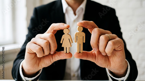 Man in black suit holding wooden figures of woman and man image